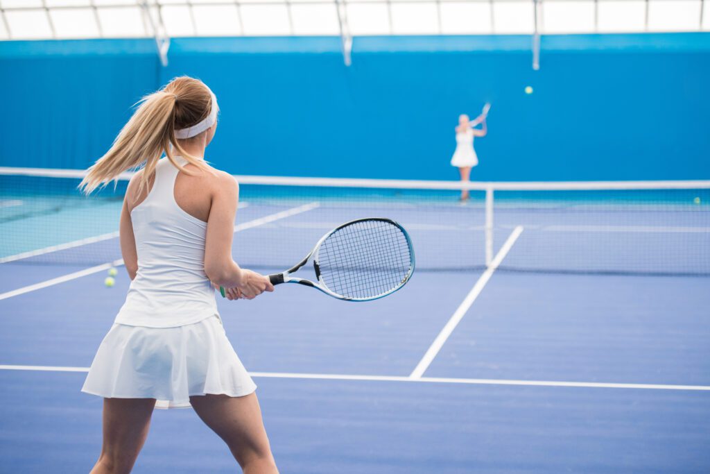 Two girls playing tennis in court